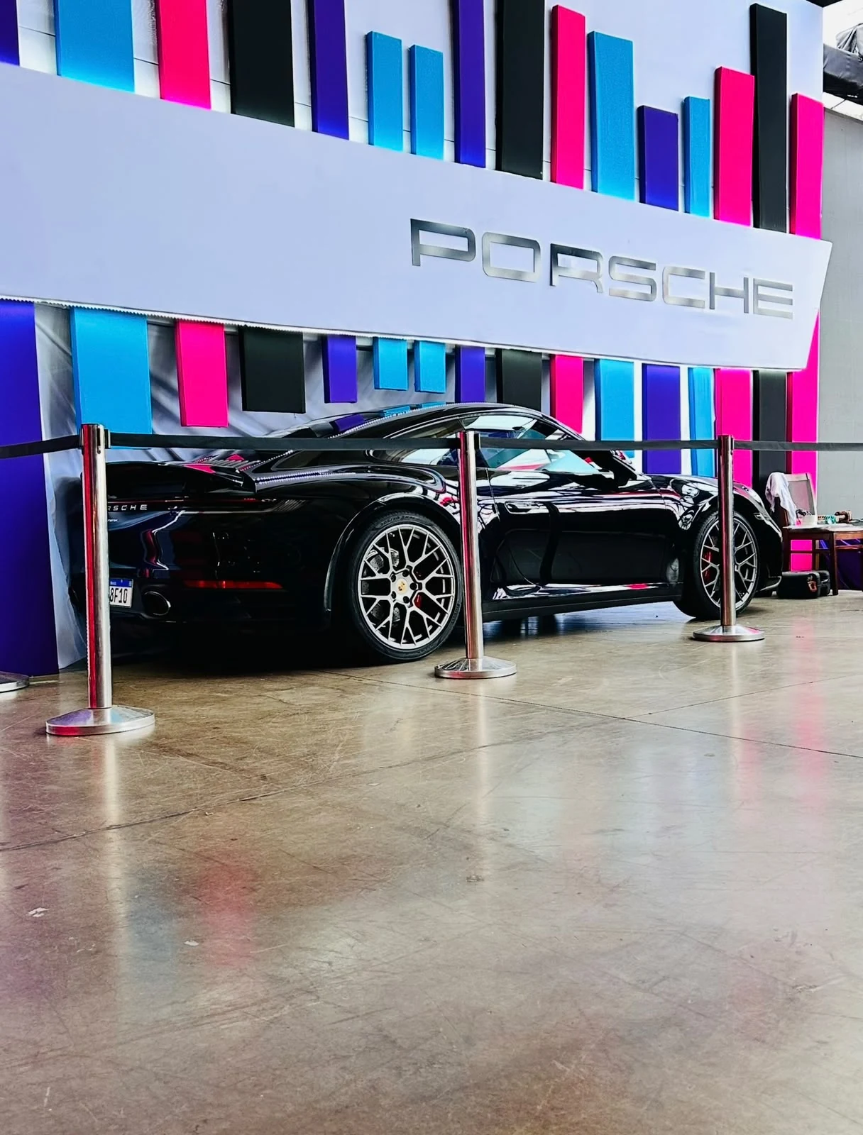 Porsche 911 preto exposto em um espaço de eventos.